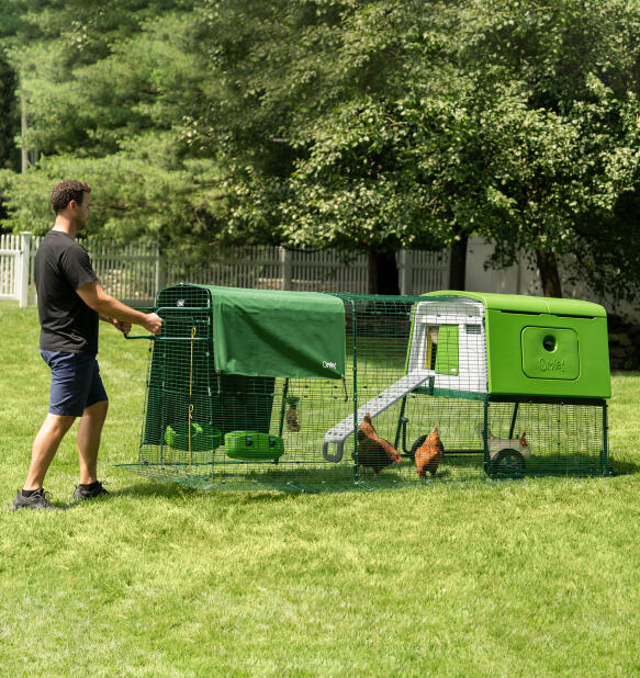 Uomo che sposta il pollaio portatile Eglu Cube con ruote e maniglie